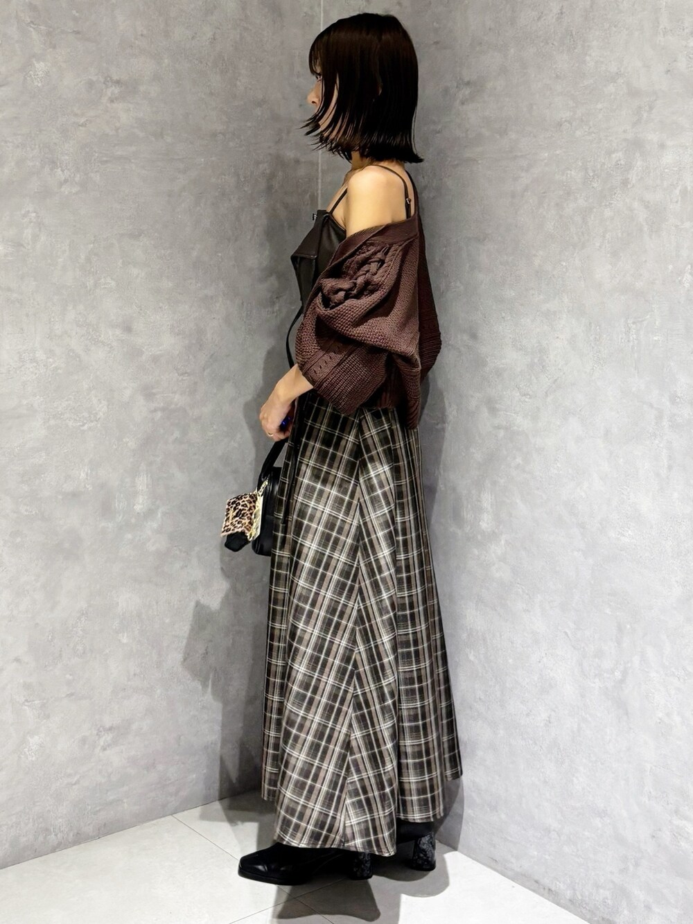 ブラウン系のワンピース、ブラック系のブーツ、ブラック系のハンドバッグを着用したレディースの秋コーディネートの6枚目の写真