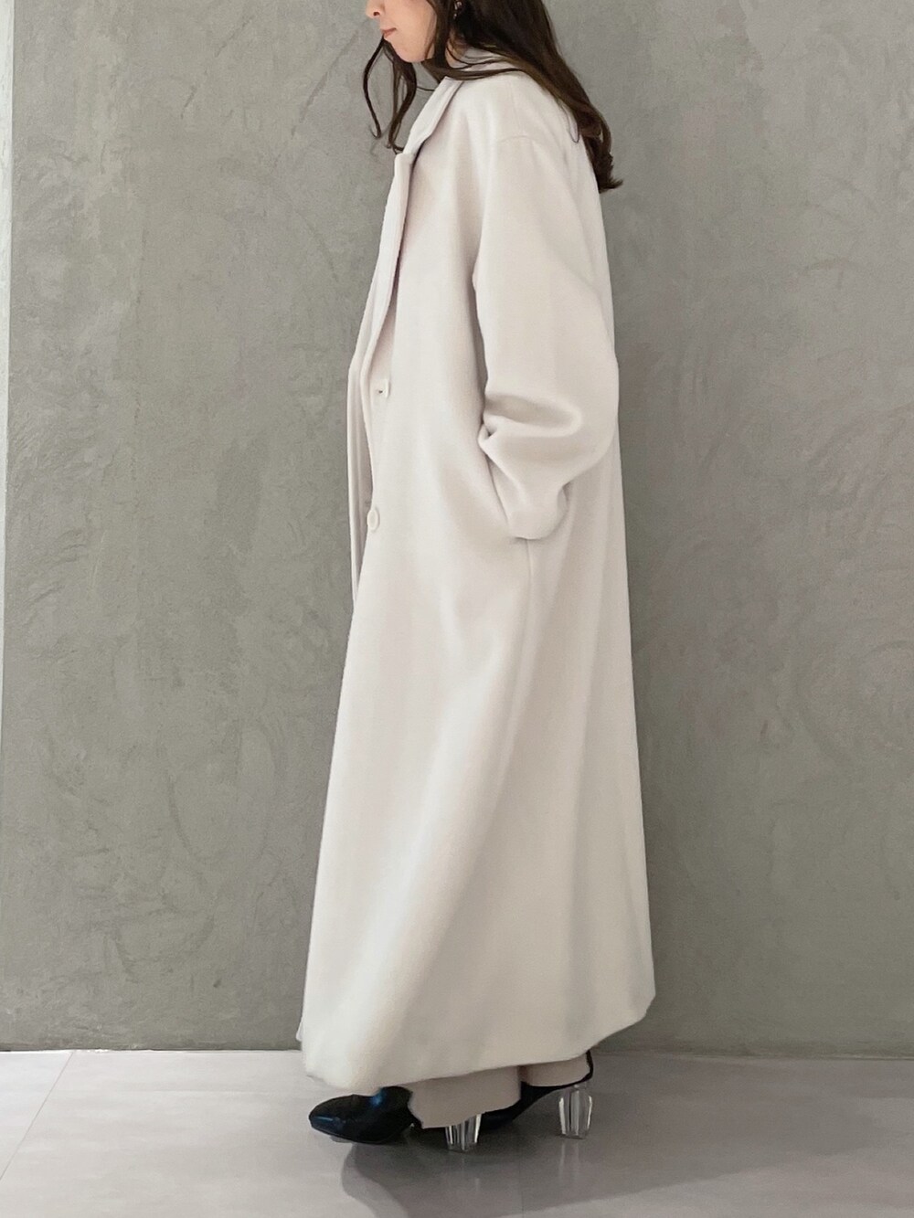 ベージュ系のワンピース、ホワイト系のチェスターコート、ブラック系のブーツを着用したレディースの冬コーディネートの2枚目の写真