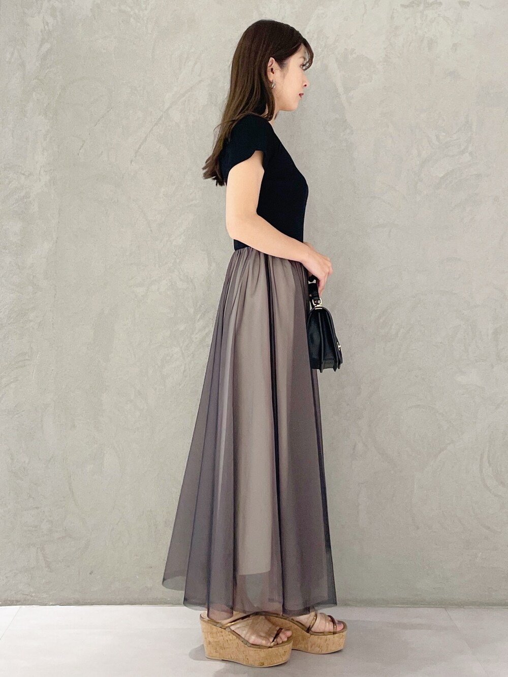 ブラウン系のサンダル、ブラック系のハンドバッグ、ブラック系のワンピースを着用したレディースの春コーディネートの3枚目の写真