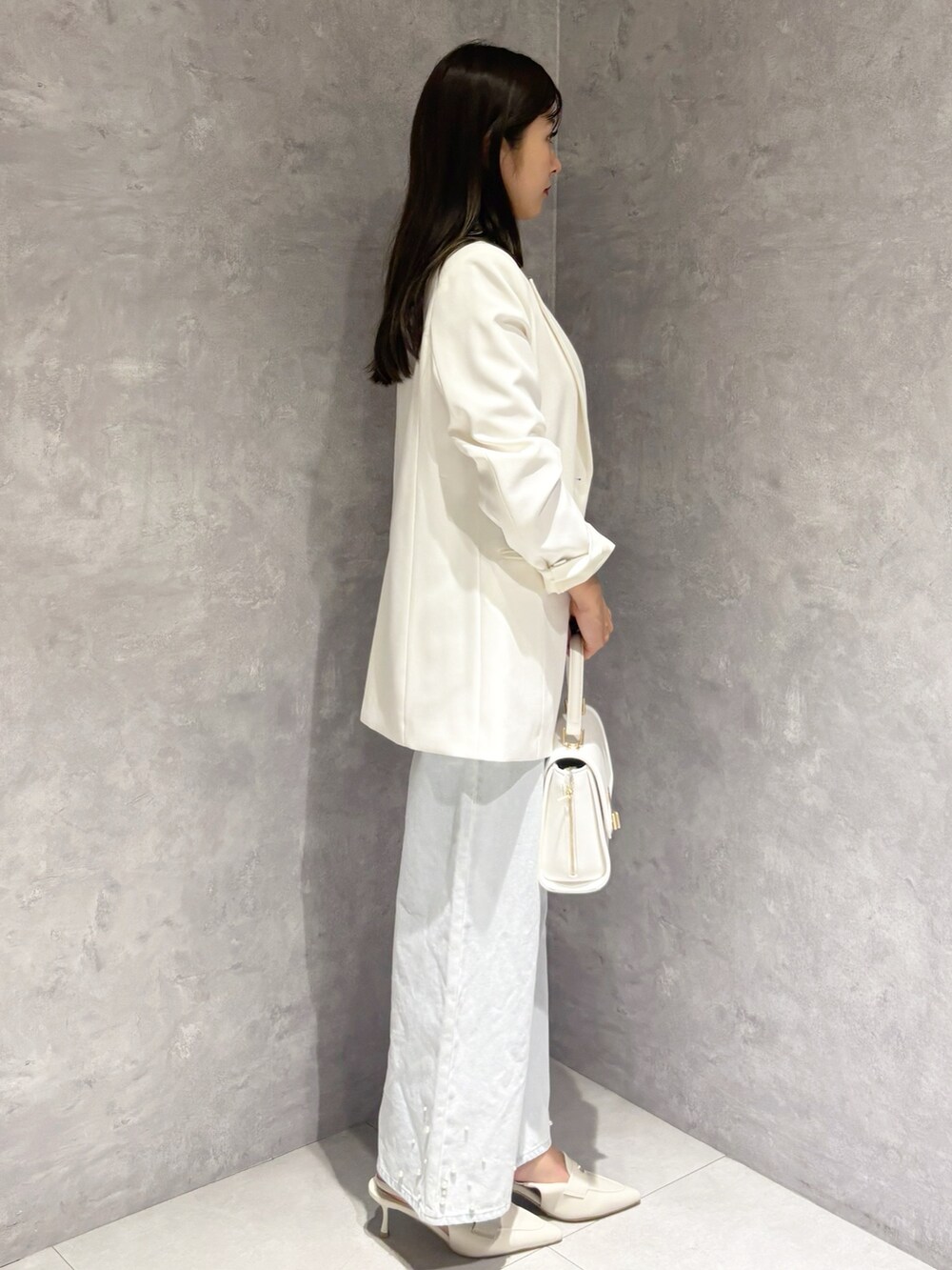 ブルー系のデニムパンツ、ホワイト系のパンプス、ホワイト系のハンドバッグを着用したレディースの冬コーディネートの4枚目の写真