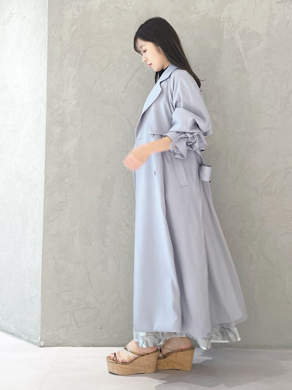 ブルー系のトレンチコート、ブラウン系のサンダル、ホワイト系のショルダーバッグを着用したレディースの春コーディネートの2枚目の写真