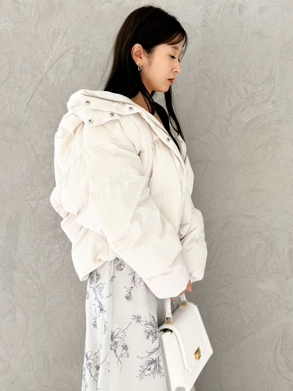 ブラック系のワンピース、ブラック系のブーツ、ホワイト系のハンドバッグを着用したレディースの秋コーディネートの2枚目の写真