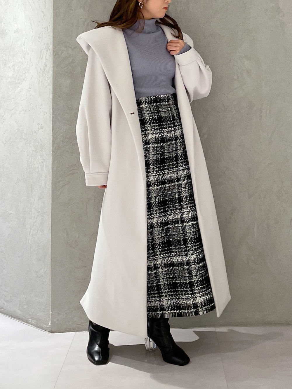 ブルー系のニット/セーター、ブラック系のスカート、ホワイト系のチェスターコートを着用したレディースの冬コーディネートの2枚目の写真