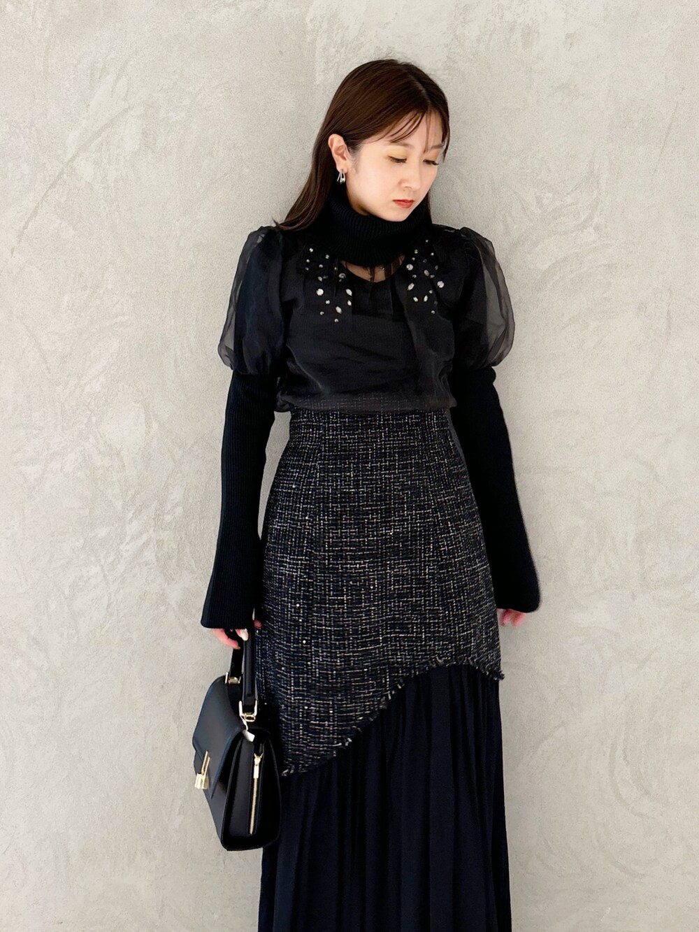 ブラック系のスカート、ブラック系のショルダーバッグ、ブラック系のブーツを着用したレディースの秋コーディネートの2枚目の写真