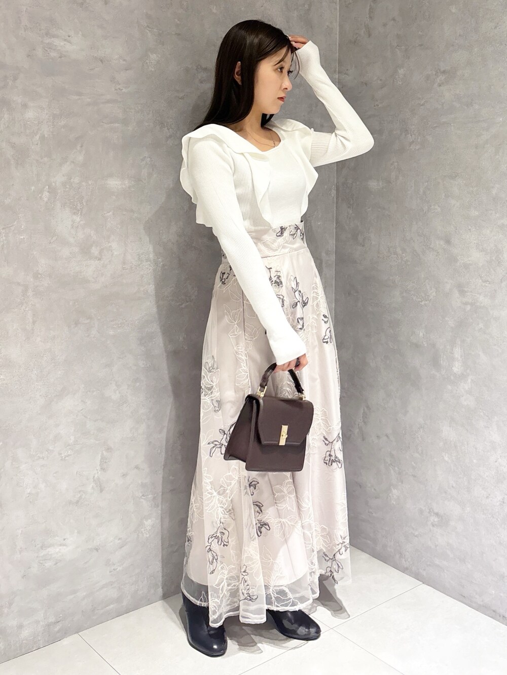 ブラウン系のハンドバッグ、ブラック系のブーツ、ベージュ系のスカートを着用したレディースの冬コーディネートの2枚目の写真