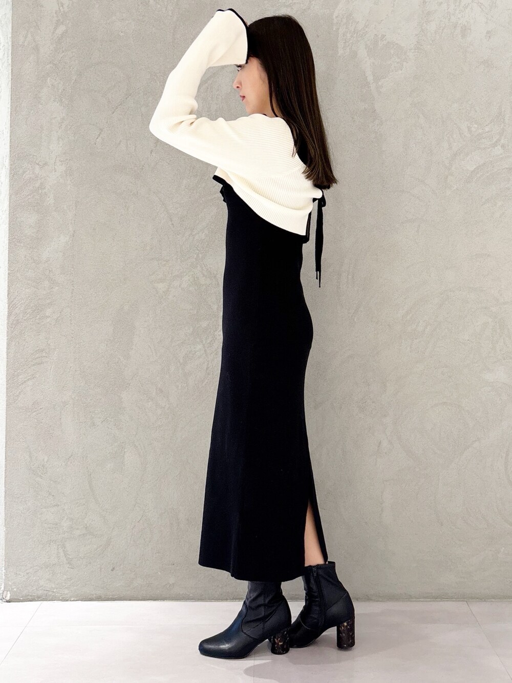 ブラック系のブーツ、ホワイト系のハンドバッグ、ブラック系のワンピースを着用したレディースの冬コーディネートの5枚目の写真