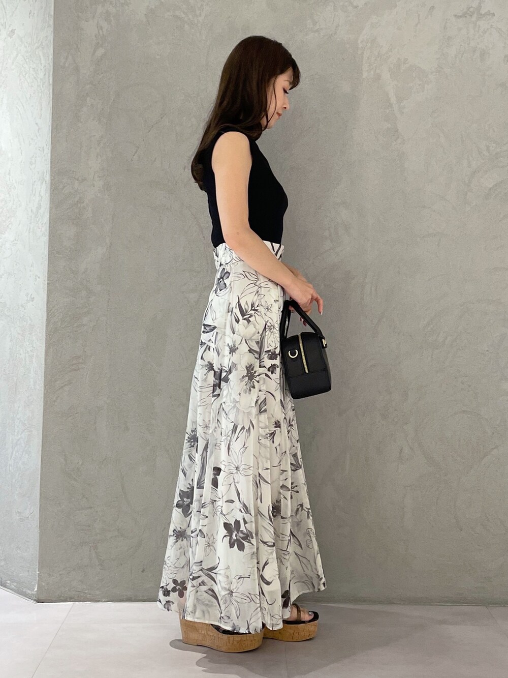 ホワイト系のボストンバッグ、ホワイト系のスカート、ブラック系のニット/セーターを着用したレディースの春コーディネートの2枚目の写真