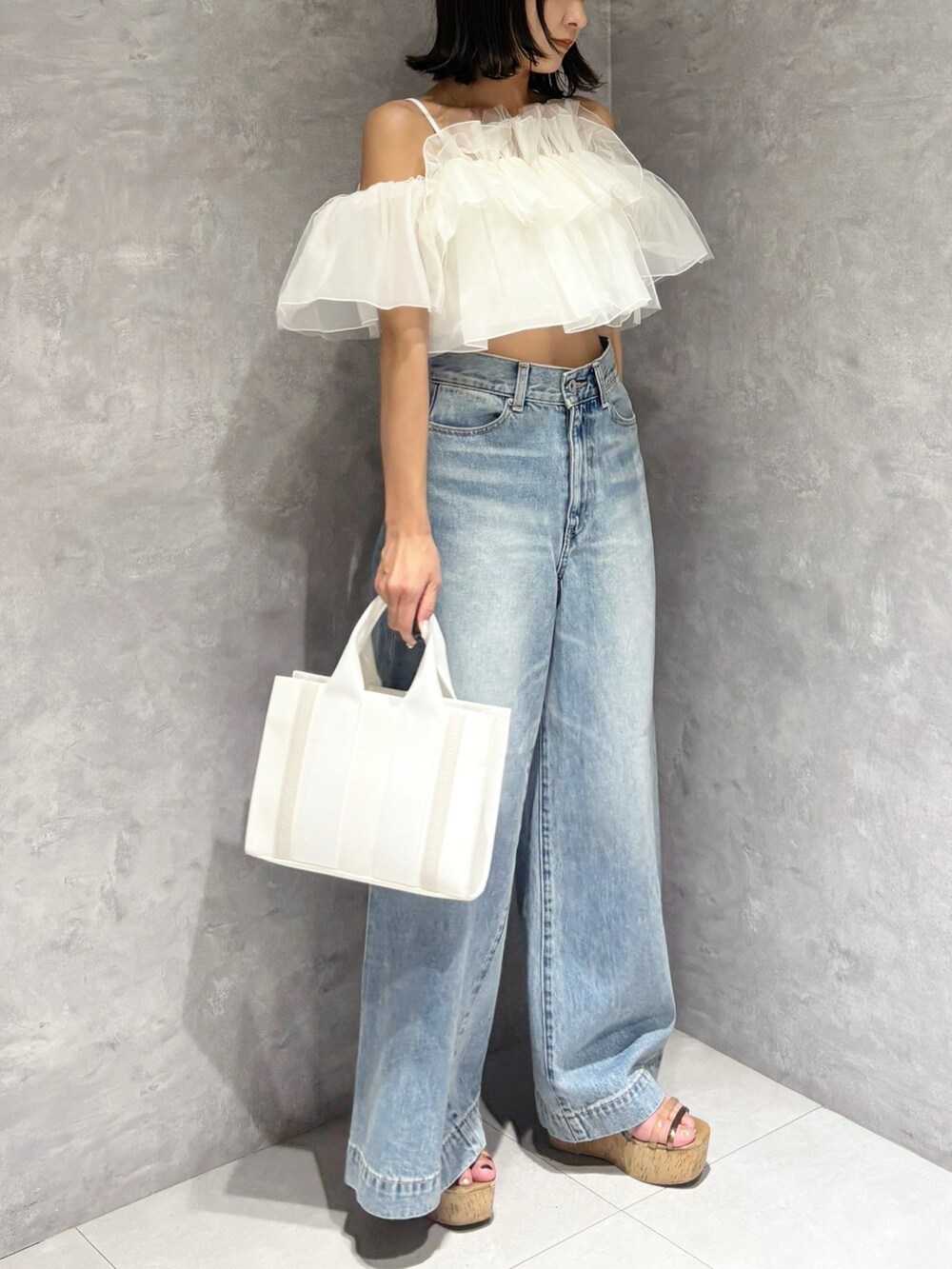 ブルー系のデニムパンツ、ブラウン系のサンダル、ホワイト系のトートバッグを着用したレディースの春コーディネートの6枚目の写真