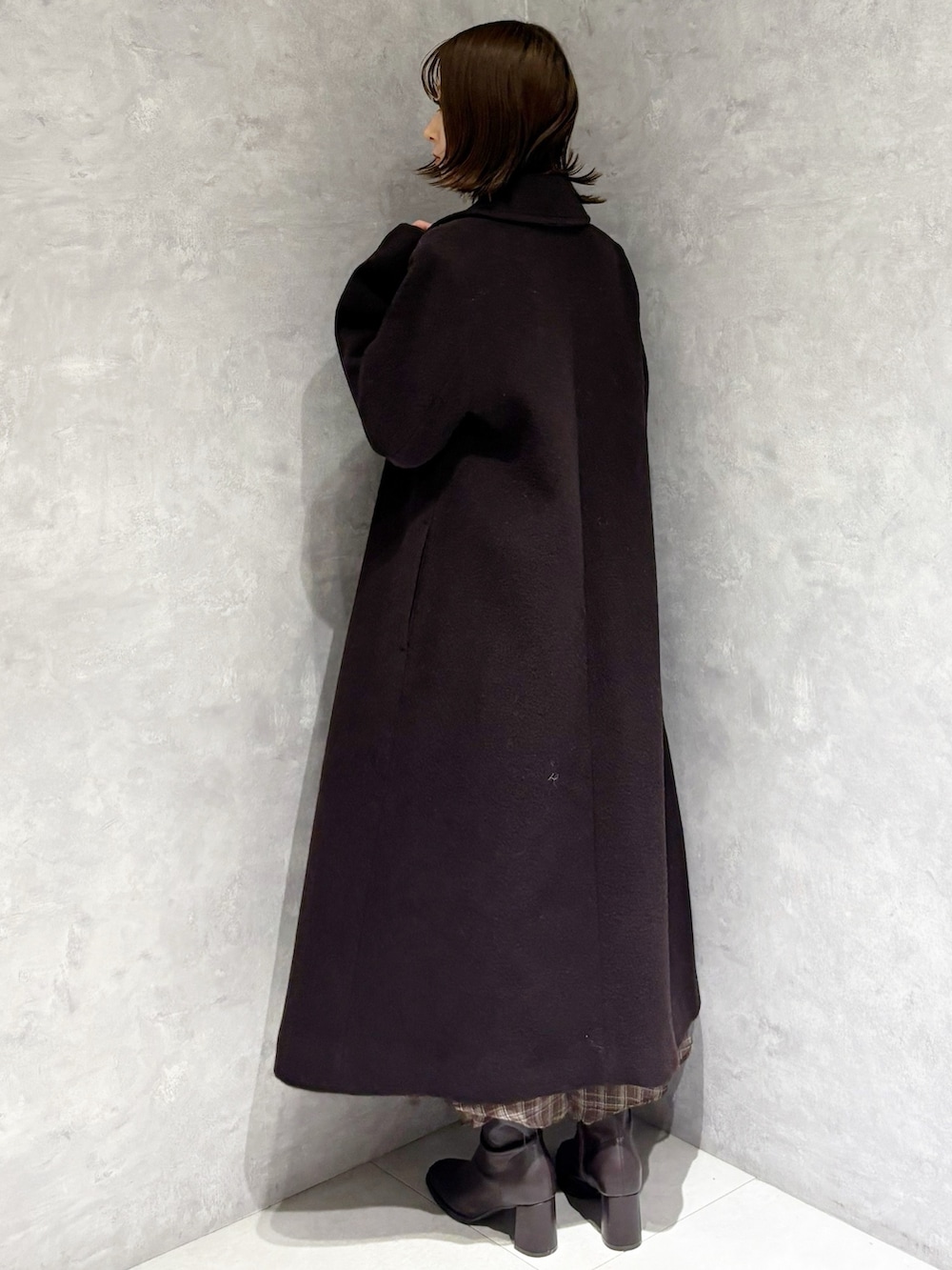 ブラウン系のチェスターコート、ブラウン系のワンピース、ブラウン系のブーツを着用したレディースの冬コーディネートの4枚目の写真