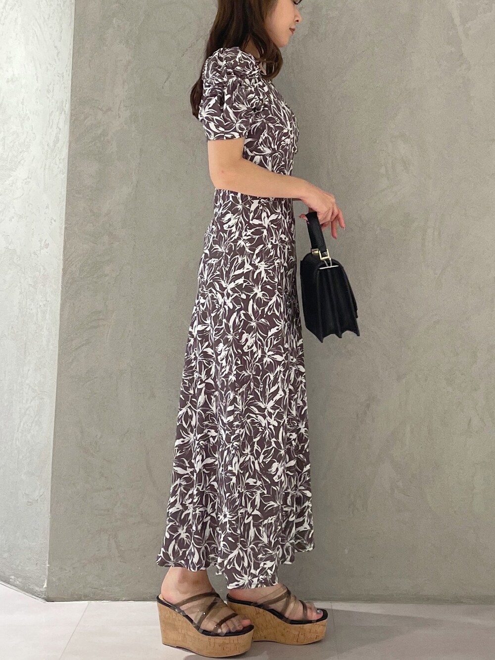 ブラック系のサンダル、ブラック系のハンドバッグ、グレー系のワンピースを着用したレディースの春コーディネートの3枚目の写真