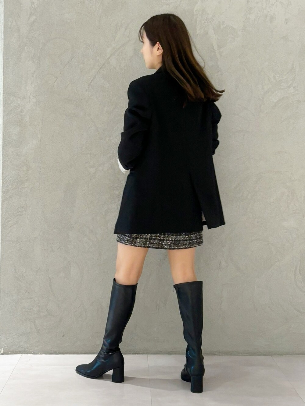 ブラック系のスカート、ブラック系のブーツ、ブラック系のショルダーバッグを着用したレディースの秋コーディネートの3枚目の写真