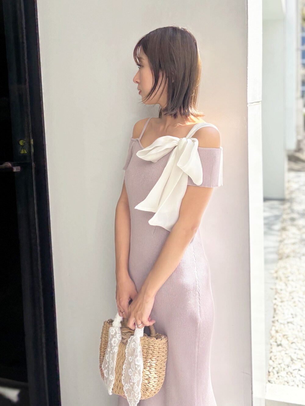 ピンク系のワンピース、ベージュ系のハンドバッグ、ホワイト系のサンダルを着用したレディースの夏コーディネートの4枚目の写真