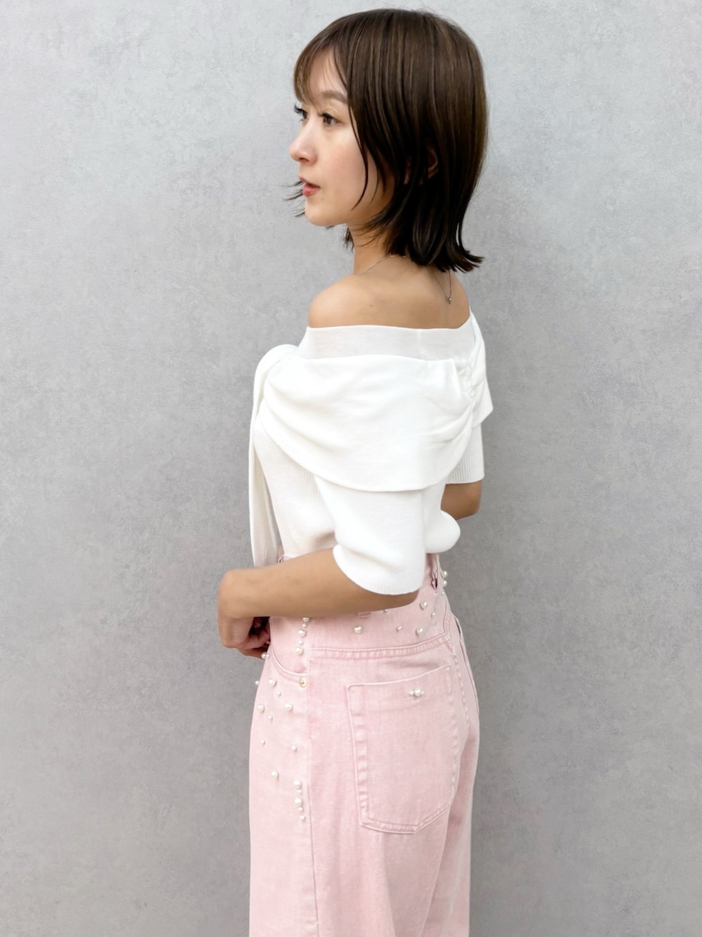 ピンク系のデニムパンツ、その他のサンダル、ホワイト系のニット/セーターを着用したレディースの春コーディネートの2枚目の写真