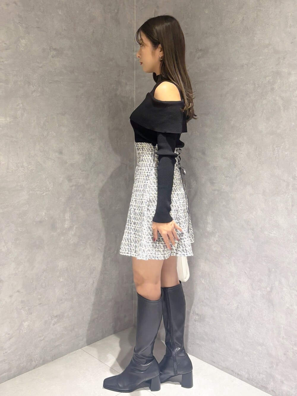 ブラック系のブーツ、ホワイト系のハンドバッグ、ブラック系のニット/セーターを着用したレディースの冬コーディネートの3枚目の写真