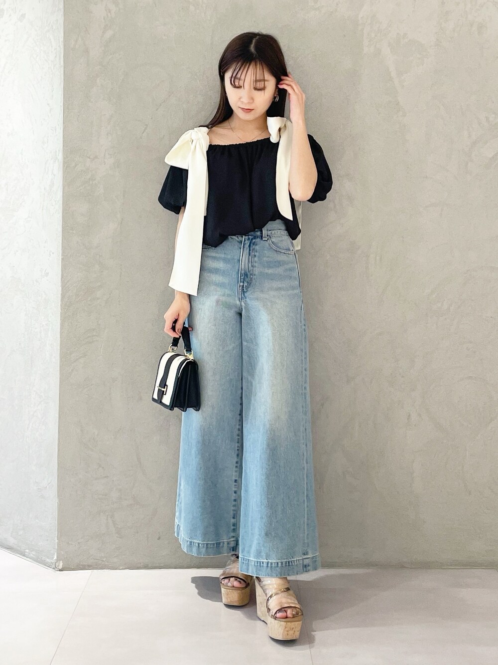 ブラウン系のサンダル、ブラック系のハンドバッグ、ブルー系のデニムパンツを着用したレディースの春コーディネートの6枚目の写真