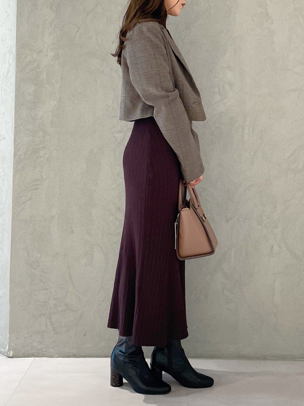 ブラウン系のワンピース、ブラック系のブーツ、ブラウン系のハンドバッグを着用したレディースの秋コーディネートの5枚目の写真