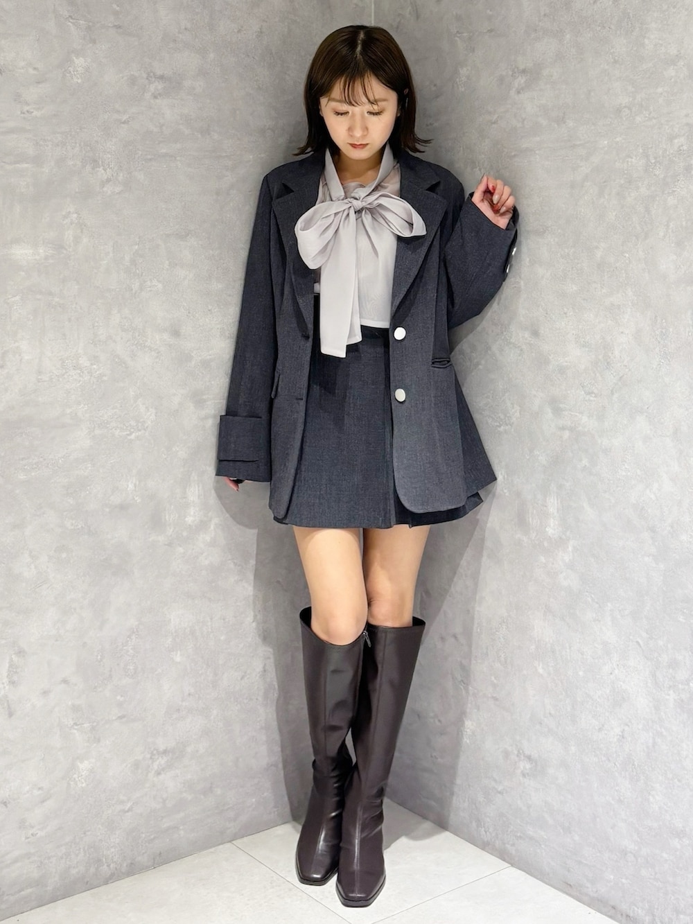 グレー系のスカート、グレー系のテーラードジャケット、ブラウン系のブーツを着用したレディースの冬コーディネートの5枚目の写真