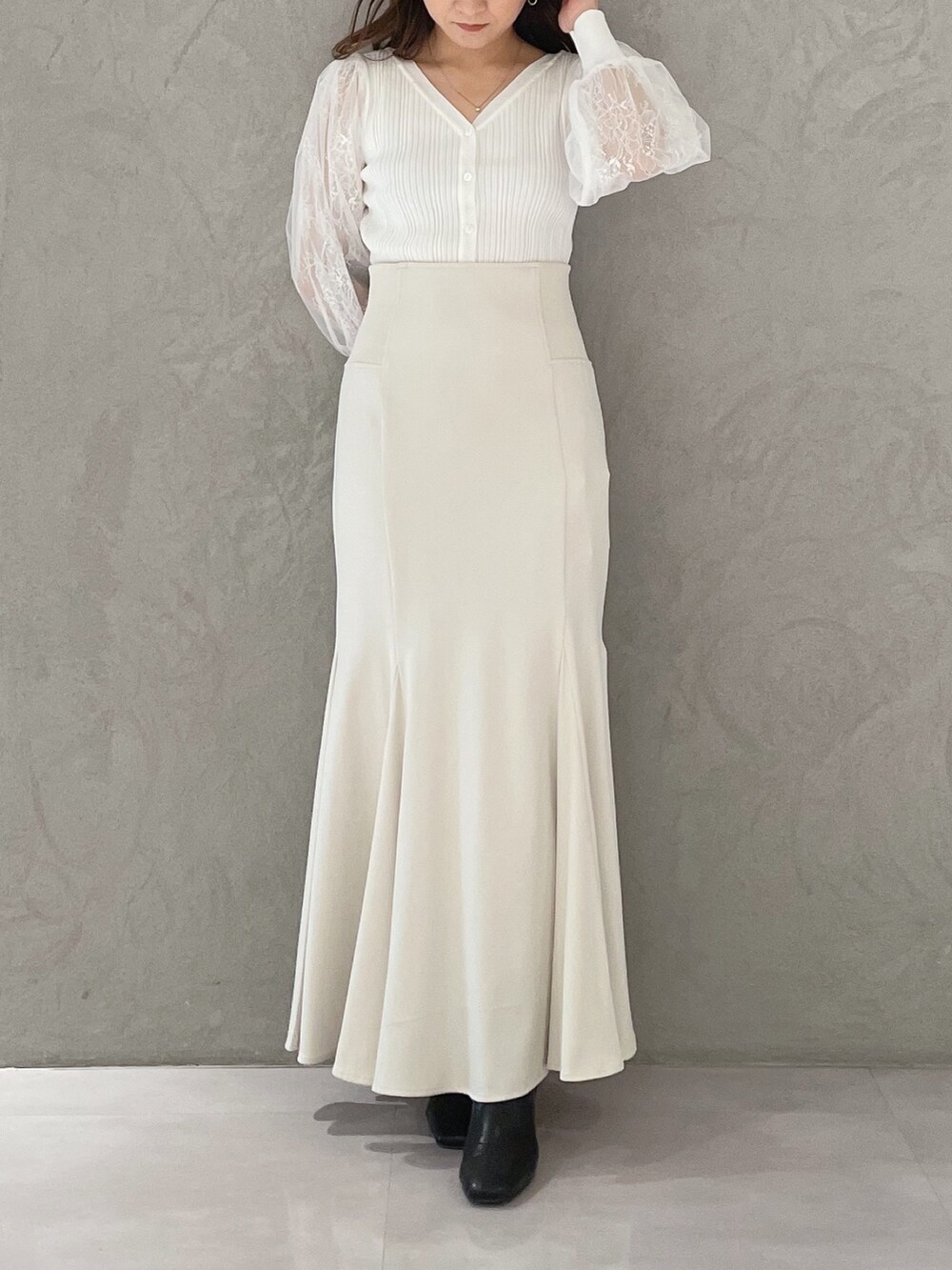 ホワイト系のスカート、ホワイト系のカーディガン/ボレロ、ブラック系のブーツを着用したレディースの冬コーディネートの7枚目の写真