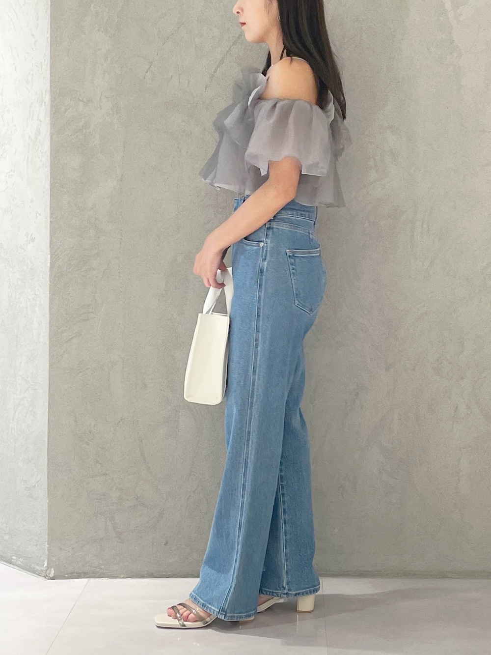 ブルー系のデニムパンツ、ホワイト系のサンダル、ホワイト系のトートバッグを着用したレディースの夏コーディネートの3枚目の写真