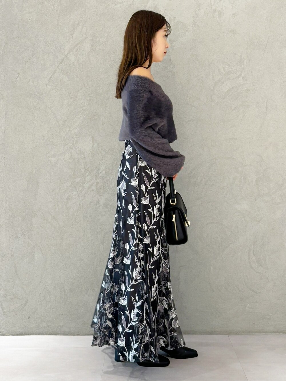 グレー系のスカート、ブラック系のブーツ、ブラック系のショルダーバッグを着用したレディースの秋コーディネートの5枚目の写真