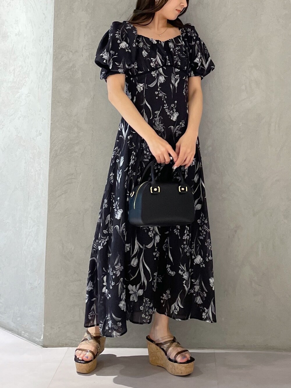 グレー系のワンピース、ブラック系のサンダルを着用したレディースの春コーディネートの2枚目の写真