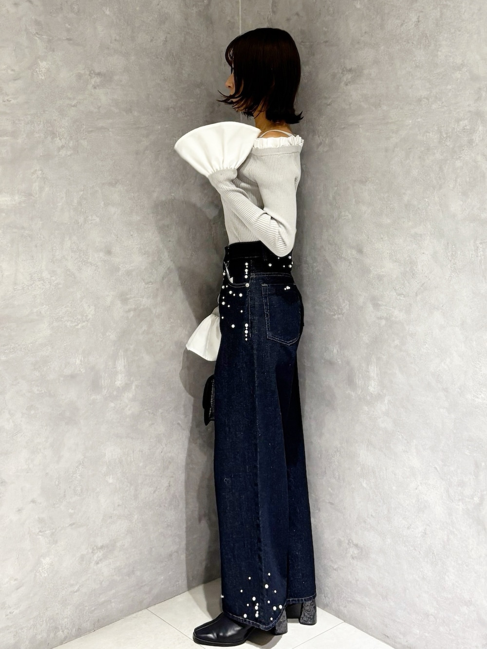 グレー系のニット/セーター、ブルー系のデニムパンツ、ブラック系のブーツを着用したレディースの秋コーディネートの5枚目の写真