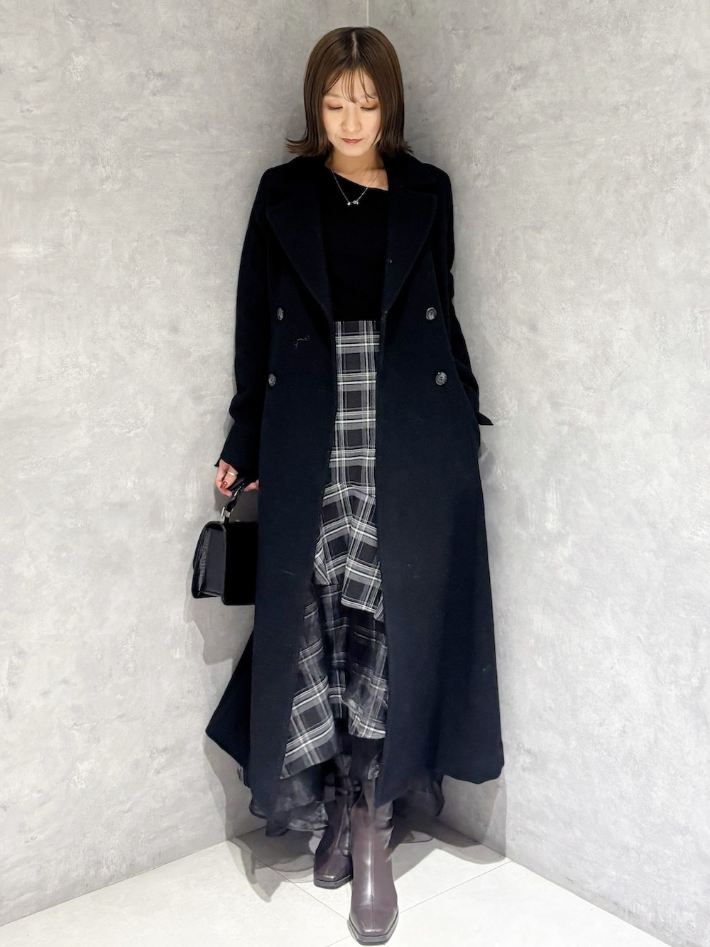 ブラック系のスカート、ブラック系のニット/セーター、ブラック系のその他アウターを着用したレディースの冬コーディネートの4枚目の写真