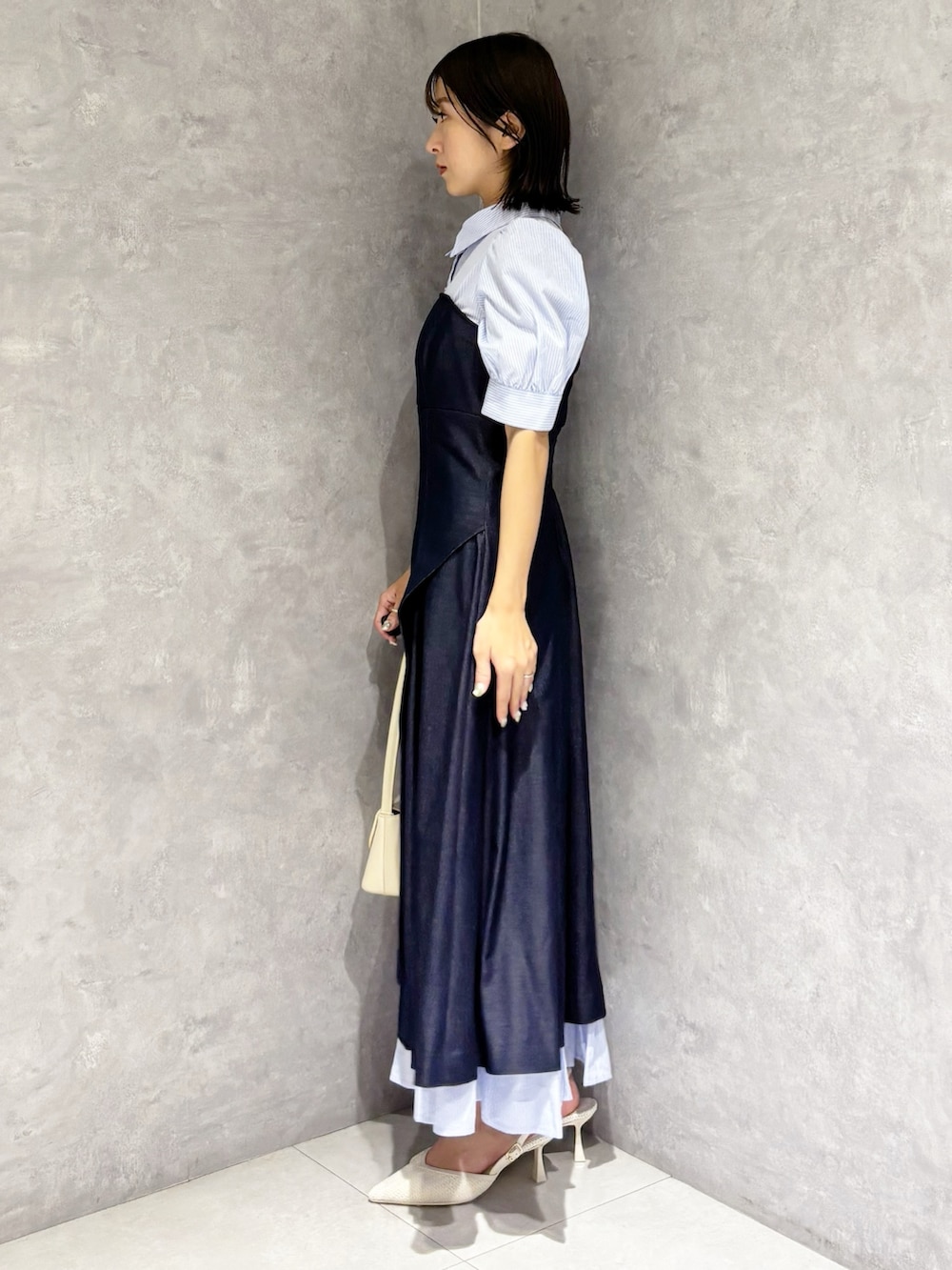 ブルー系のワンピース、ホワイト系のパンプス、ホワイト系のハンドバッグを着用したレディースの春コーディネートの3枚目の写真