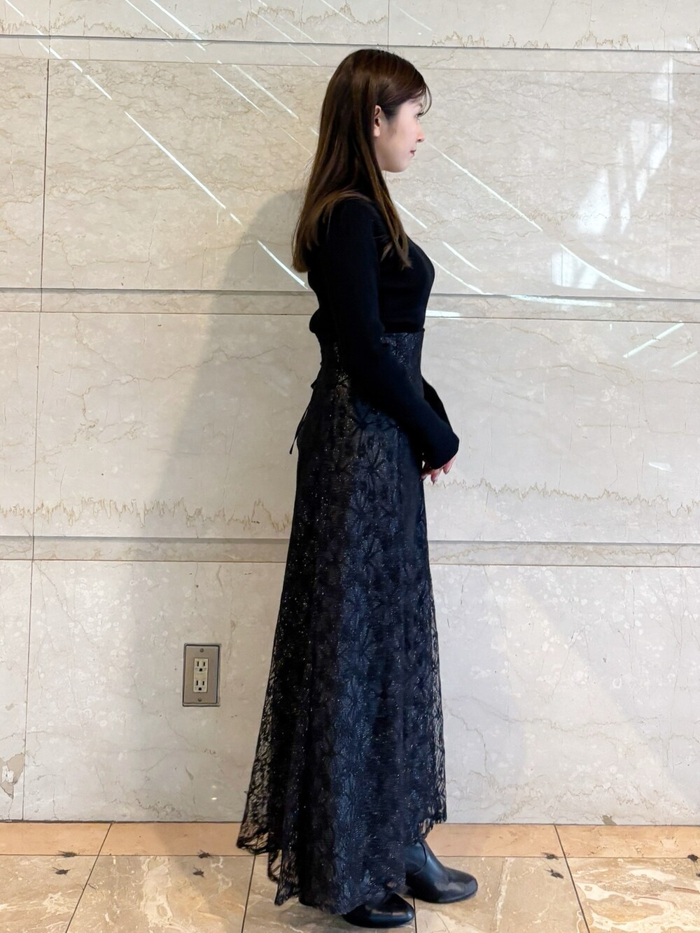 ブラック系のスカート、ブラック系のニット/セーター、ブラック系のブーツを着用したレディースの冬コーディネートの6枚目の写真