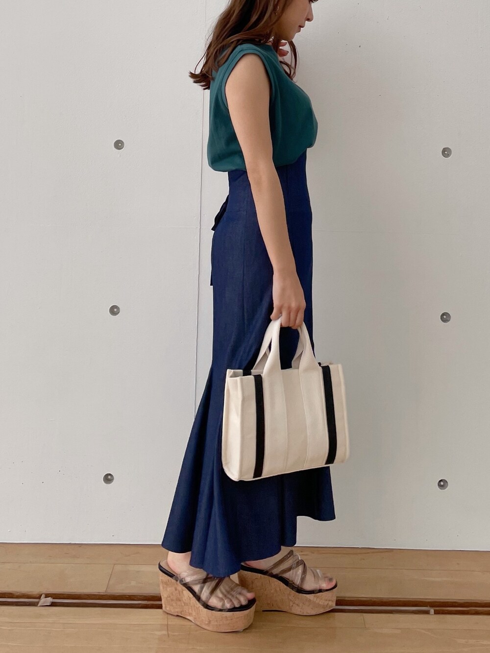 グレー系のハンドバッグ、ブラック系のサンダル、ブルー系のスカートを着用したレディースの春コーディネートの2枚目の写真