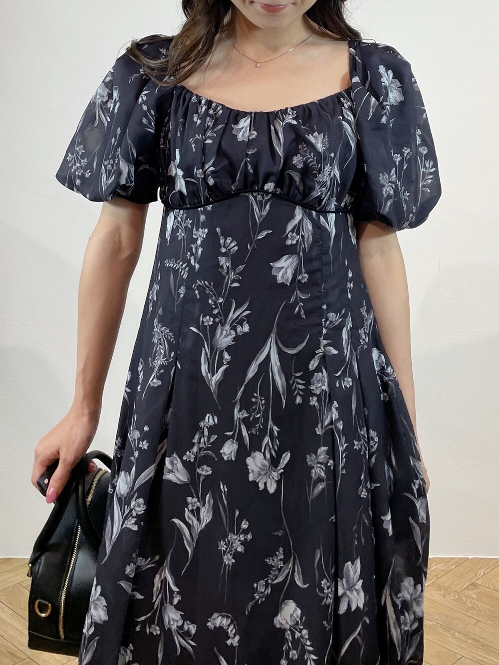 ブラック系のハンドバッグ、ブラック系のサンダル、グレー系のワンピースを着用したレディースの春コーディネートの2枚目の写真