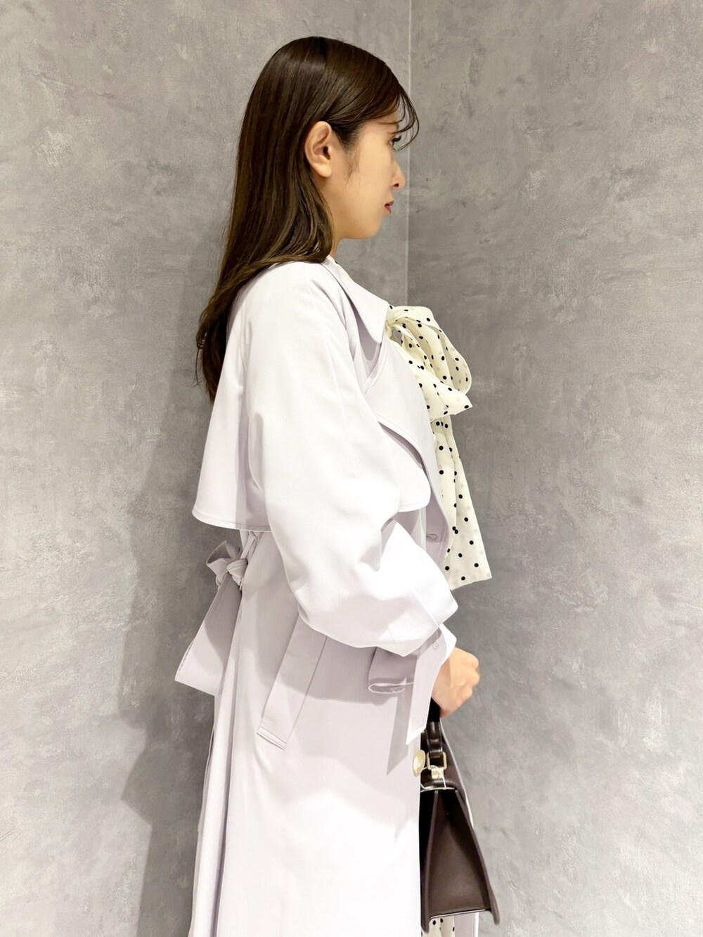 ホワイト系のワンピース、パープル系のトレンチコート、ブラウン系のハンドバッグを着用したレディースの冬コーディネートの3枚目の写真