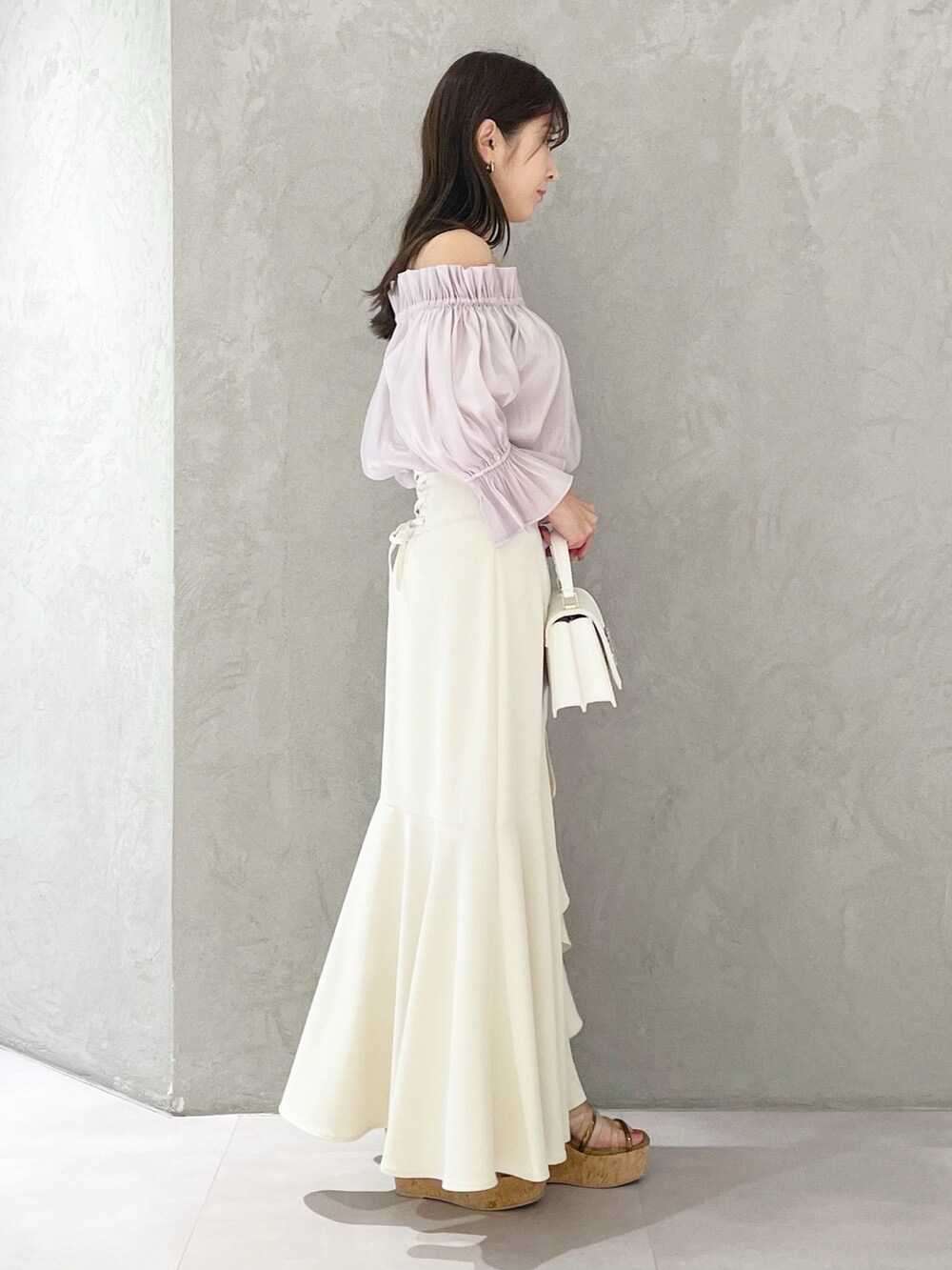 ホワイト系のスカート、ホワイト系のショルダーバッグ、ブラウン系のサンダルを着用したレディースの春コーディネートの2枚目の写真