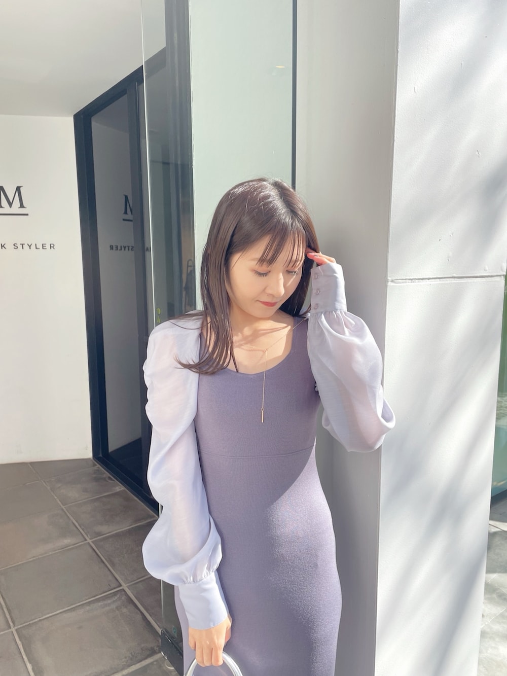 シルバー系のハンドバッグ、ブラック系のブーツ、ブルー系のワンピースを着用したレディースの春コーディネートの5枚目の写真