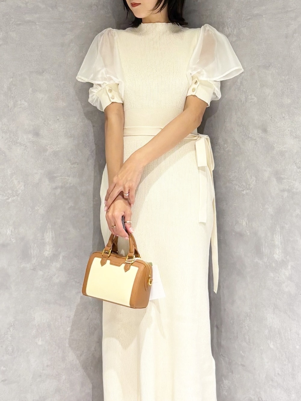 ホワイト系のワンピース、ホワイト系のパンプス、ブラウン系のハンドバッグを着用したレディースの春コーディネートの5枚目の写真