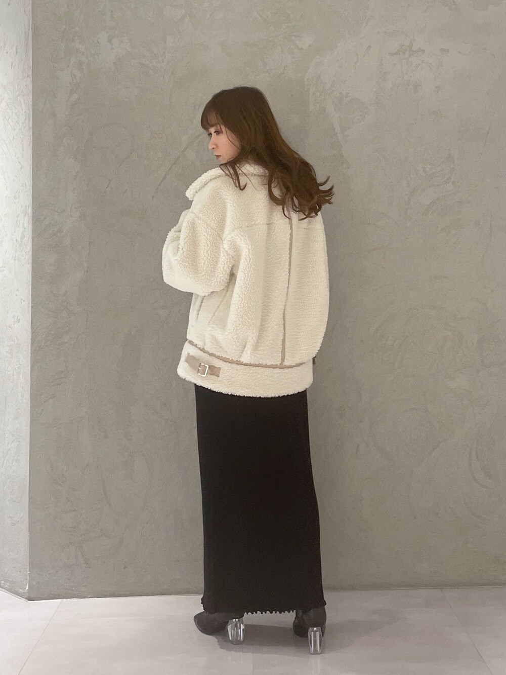 ブラック系のワンピース、ホワイト系のその他アウター、ブラック系のブーツを着用したレディースの冬コーディネートの2枚目の写真