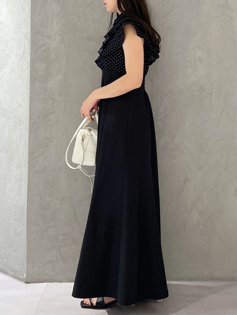 ブラック系のワンピース、ホワイト系のボストンバッグ、ブラック系のサンダルを着用したレディースの春コーディネートの2枚目の写真