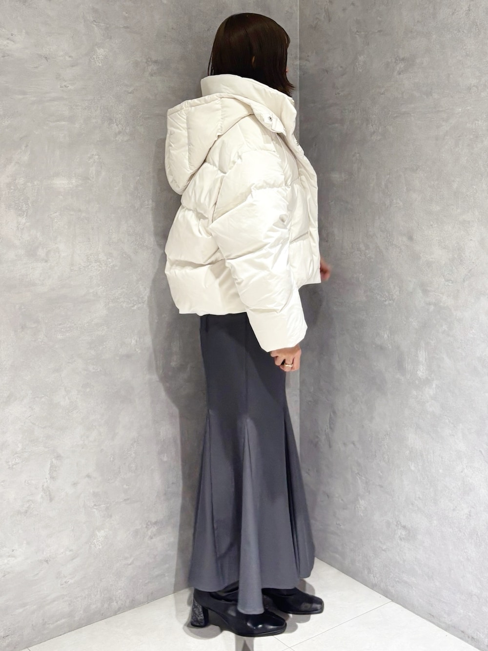 グレー系のスカート、グレー系のニット/セーター、ホワイト系のダウンジャケット/コートを着用したレディースの冬コーディネートの4枚目の写真