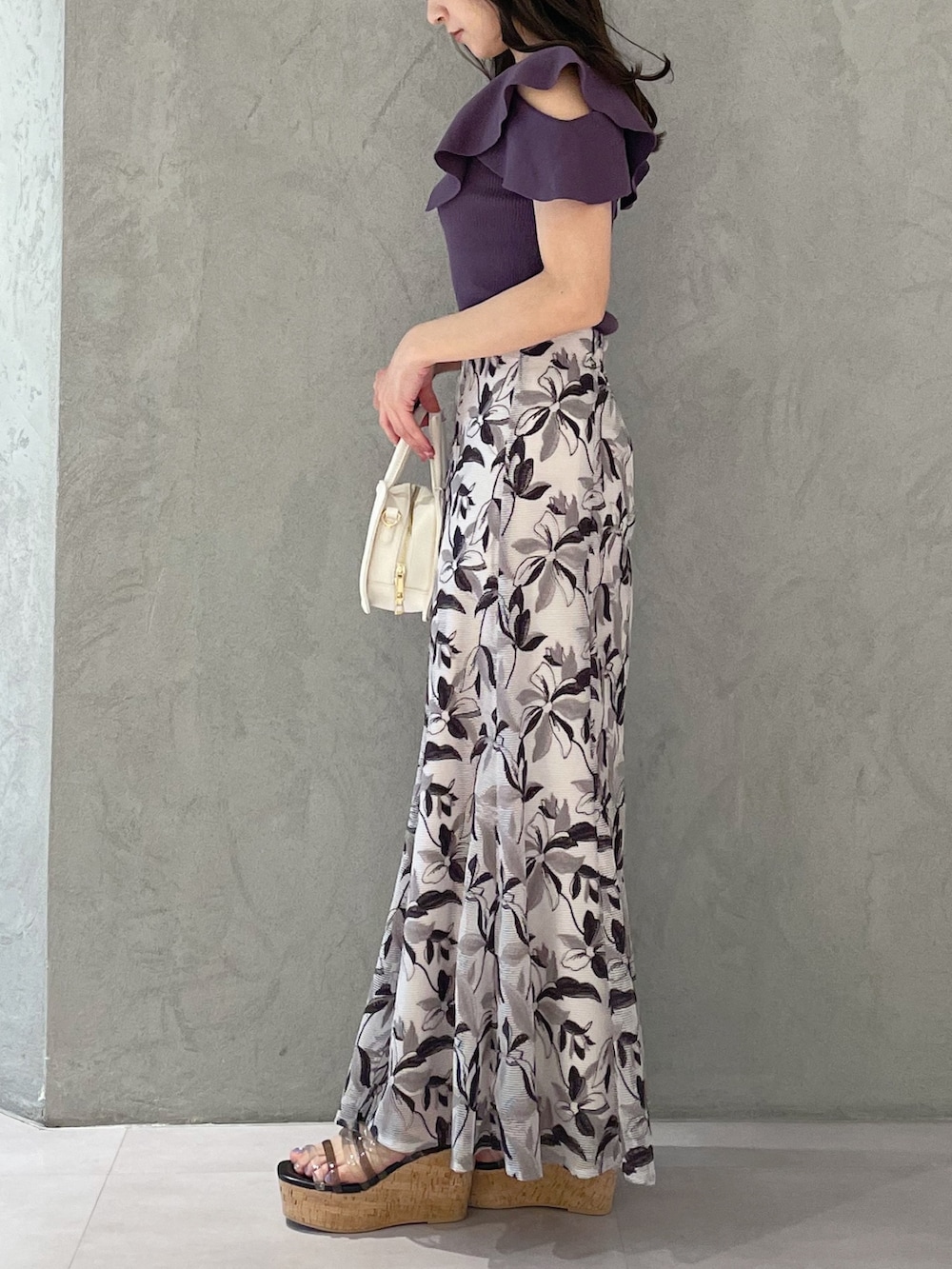 ホワイト系のハンドバッグ、ブラック系のサンダル、パープル系のニット/セーターを着用したレディースの春コーディネートの6枚目の写真