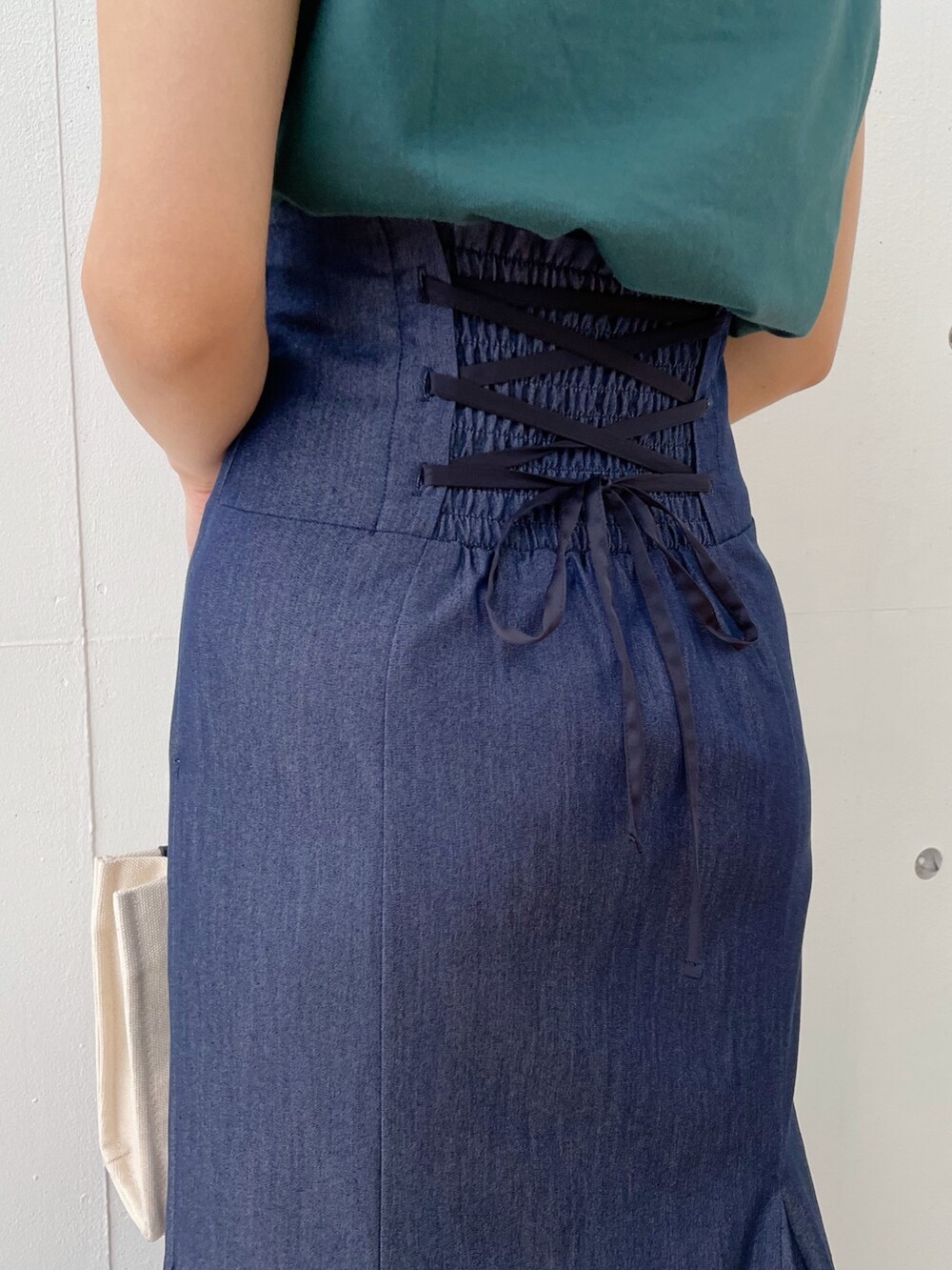 グレー系のハンドバッグ、ブラック系のサンダル、ブルー系のスカートを着用したレディースの春コーディネートの6枚目の写真