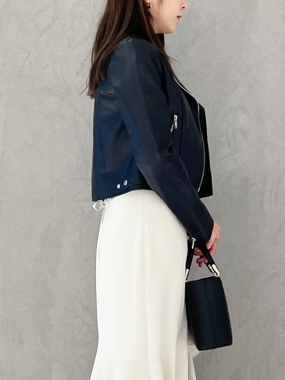 ブラック系のハンドバッグ、ブラック系のブーツ、ブラック系のライダースジャケットを着用したレディースの冬コーディネートの5枚目の写真