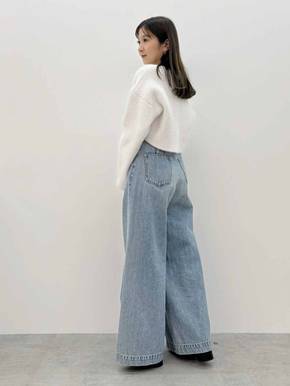 ブルー系のデニムパンツ、ブラック系のブーツ、ホワイト系のカーディガン/ボレロを着用したレディースの秋コーディネートの5枚目の写真