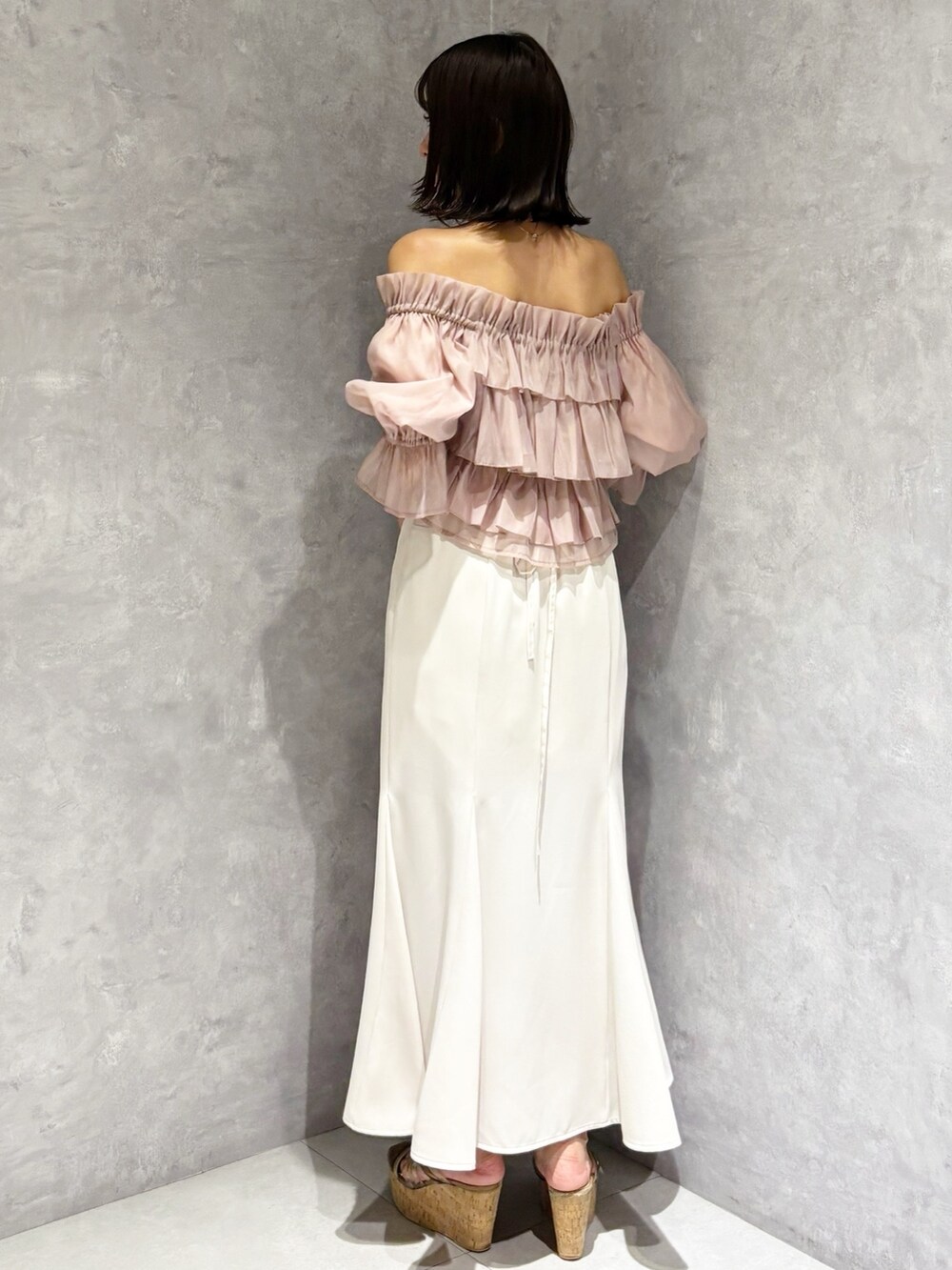 ホワイト系のスカート、ブラウン系のサンダル、ホワイト系のハンドバッグを着用したレディースの夏コーディネートの2枚目の写真