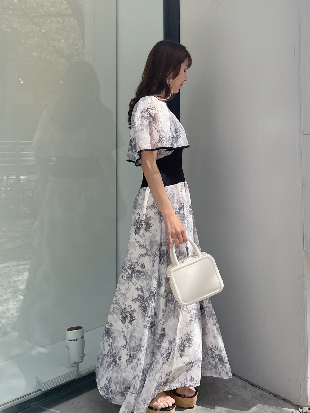 ブラック系のサンダル、ホワイト系のハンドバッグ、ホワイト系のワンピースを着用したレディースの春コーディネートの4枚目の写真