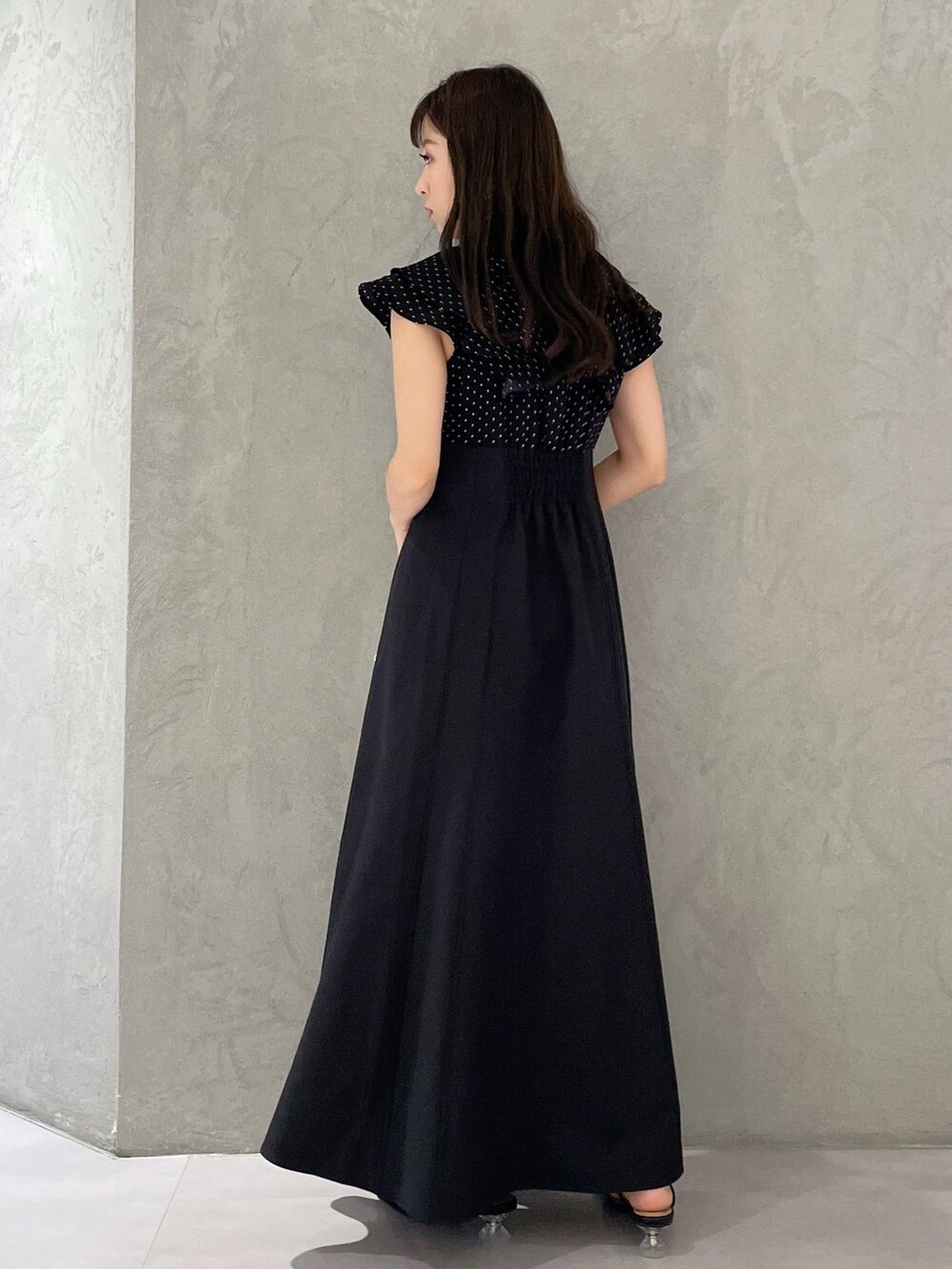 ブラック系のワンピース、ホワイト系のボストンバッグ、ブラック系のサンダルを着用したレディースの春コーディネートの3枚目の写真