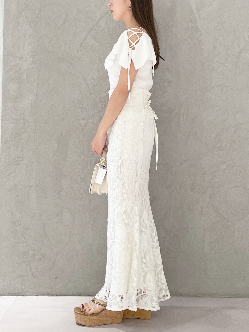 ホワイト系のハンドバッグ、ホワイト系のニット/セーター、ホワイト系のスカートを着用したレディースの春コーディネートの4枚目の写真