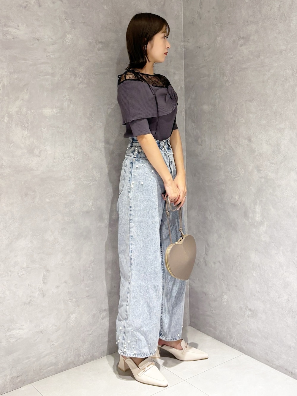 ブルー系のデニムパンツ、ホワイト系のパンプス、グレー系のニット/セーターを着用したレディースの春コーディネートの2枚目の写真