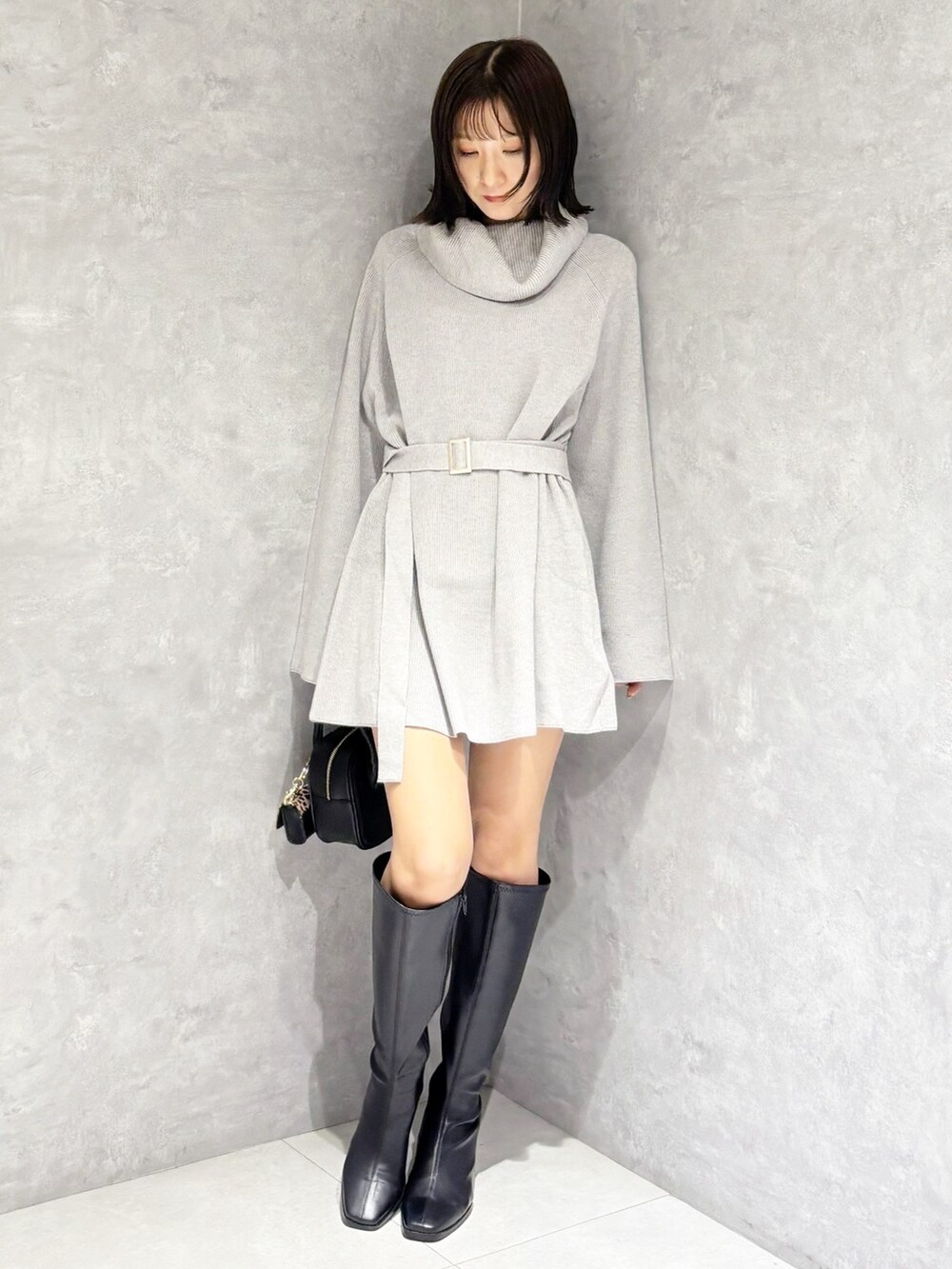 グレー系のニット/セーター、ブラック系のブーツ、ブラック系のハンドバッグを着用したレディースの秋コーディネートの5枚目の写真