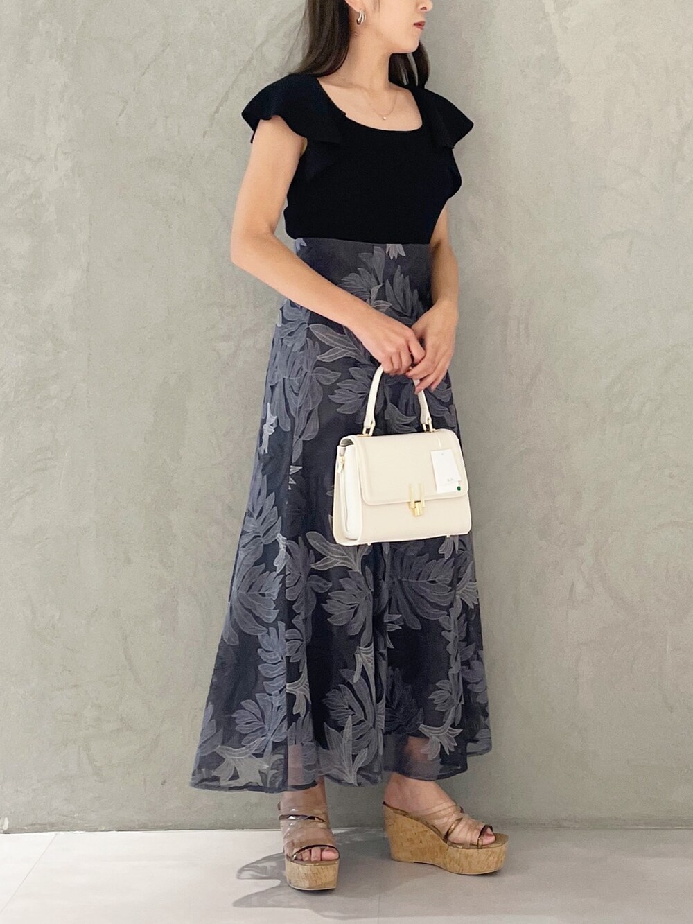 ブラック系のニット/セーター、ホワイト系のショルダーバッグ、ブラウン系のサンダルを着用したレディースの夏コーディネートの4枚目の写真