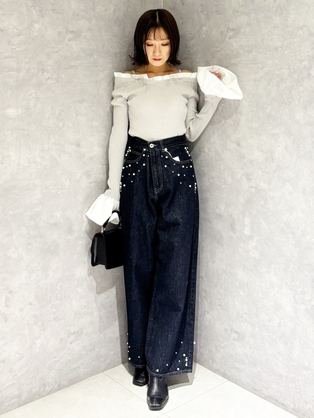 グレー系のニット/セーター、ブルー系のデニムパンツ、ブラック系のブーツを着用したレディースの秋コーディネートの6枚目の写真